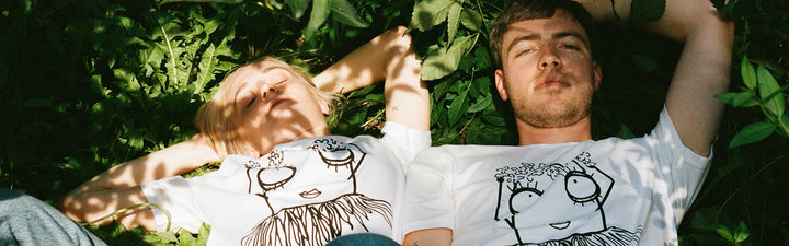 Pärchen liegt in der Wiese mit weißen Quipster Hula T-Shirts 